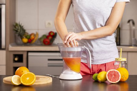 Photo for Detail of female hands holding a grapefruit half and making a freshly squeezed mixed citrus fruit with the help of a citrus juicer - Royalty Free Image