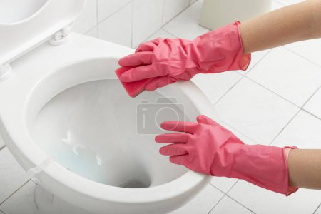 Foto de Acercamiento de las manos femeninas con guantes protectores, fregar el inodoro con esponja - Imagen libre de derechos