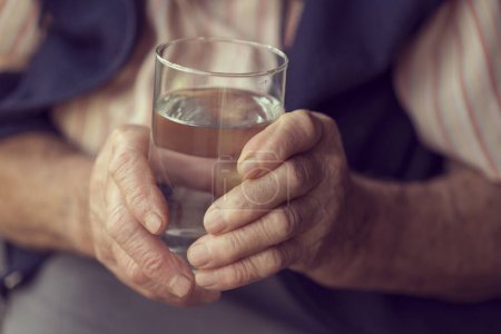 Téléchargez les photos : Gros plan des mains d'une femme âgée tenant un verre d'eau - en image libre de droit