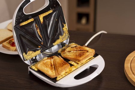 Téléchargez les photos : Détail des sandwichs chauds prêts à manger dans une machine à sandwich. Focus sélectif sur les sandwichs - en image libre de droit