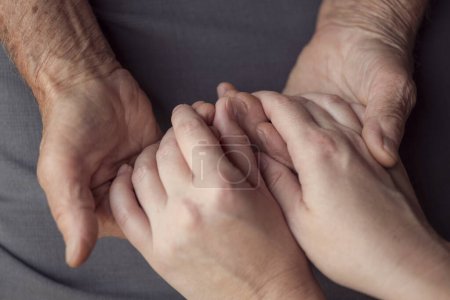 Photo for Old and young person holding hands. Elderly care and respect, selective focus - Royalty Free Image