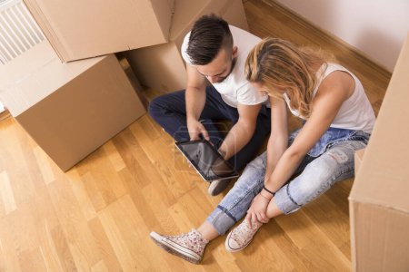 Téléchargez les photos : Jeune couple amoureux déménageant dans un nouvel appartement, assis sur le sol, prévoyant de redécorer leur nouvelle maison. Vue du dessus - en image libre de droit