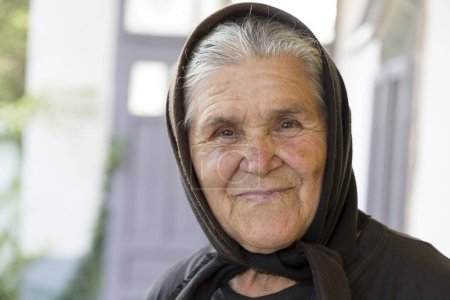 Téléchargez les photos : Portrait d'une femme âgée portant un foulard, regardant la caméra et souriant - en image libre de droit