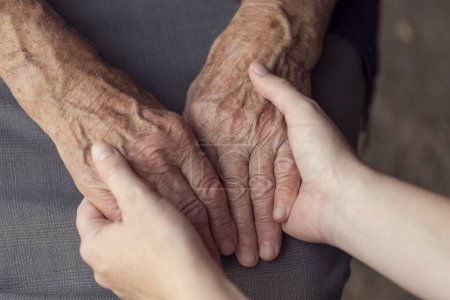 Foto de Old and young person holding hands. Elderly care and respect, selective focus - Imagen libre de derechos