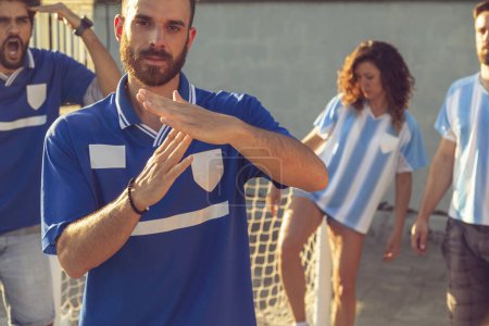 Photo for Group of people playing football, one of the players asking for time out after a foul; people angry and fighting while playing football - Royalty Free Image