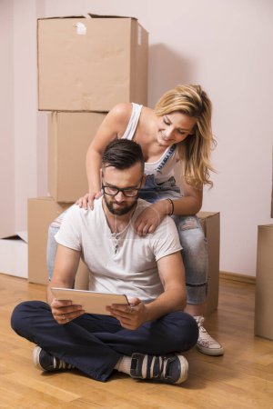 Photo for Young couple in love moving in a new apartment, sitting on the floor, planning to redecorate their new home - Royalty Free Image