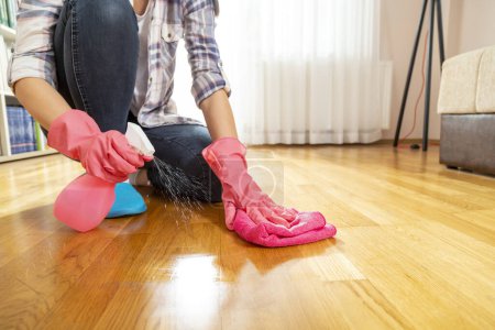 Téléchargez les photos : Détail de la femme portant des gants de protection et le sol de nettoyage avec nettoyant désinfecté plancher - en image libre de droit