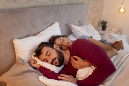 Photo for Couple in love wearing pajamas, lying hugged in bed, sleeping - Royalty Free Image