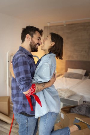 Téléchargez les photos : Beau jeune couple amoureux s'amuser tout en emménageant ensemble, embrasser et embrasser dans leur nouvelle maison - en image libre de droit