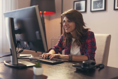 Téléchargez les photos : Jeune programmeuse travaillant dans un bureau à domicile, tapant sur un clavier - en image libre de droit