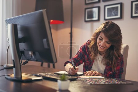 Photo for Female graphic designer working in a home office, choosing a color from a color palette - Royalty Free Image