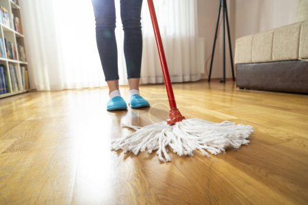 Foto de Detalle de la mujer sosteniendo un limpiaparabrisas y limpiando el piso, haciendo el trabajo de la casa y manteniendo la higiene diaria del hogar - Imagen libre de derechos