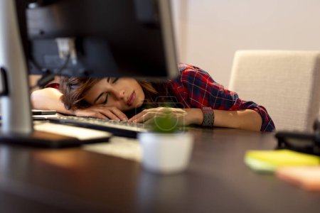 Photo for Young woman worn out because of working overtime, asleep at a desk at her home office - Royalty Free Image