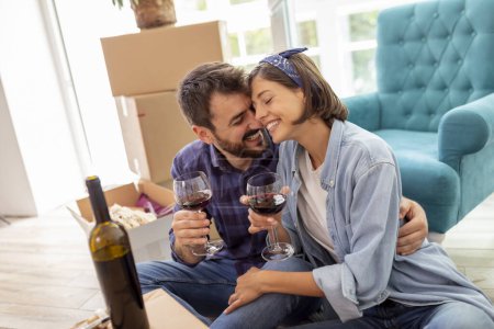 Photo for Beautiful young couple in love celebrating moving in new home, drinking wine, laughing and having fun - Royalty Free Image