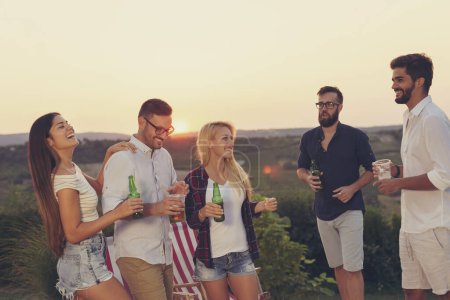 Foto de Grupo de amigos divirtiéndose en una fiesta de verano junto a la piscina, bailando y bebiendo cerveza - Imagen libre de derechos