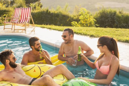 Téléchargez les photos : Groupe d'amis à une fête d'été au bord de la piscine, s'amuser dans la piscine, boire des cocktails et de la bière et se détendre - en image libre de droit