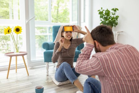 Photo for Couple having fun at home playing charades, explaining and guessing the words from a smart phone app - Royalty Free Image