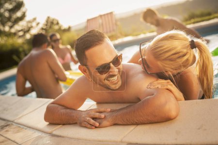 Téléchargez les photos : Couple amoureux lors d'une fête d'été au bord de la piscine, penché au bord d'une piscine, bronzer et s'amuser - en image libre de droit