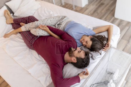 Téléchargez les photos : Couple amoureux couché au lit après le réveil, étreignant, câlinant, riant et appréciant leur temps ensemble - en image libre de droit