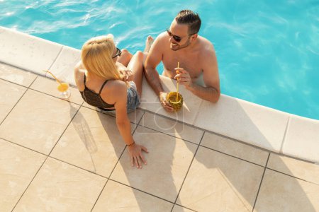 Téléchargez les photos : Vue en angle élevé d'un beau jeune couple buvant des cocktails et s'amusant dans une piscine - en image libre de droit