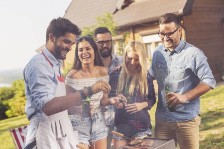 Photo for Group of friends making barbecue in the backyard, drinking beer and having fun on a sunny summer day - Royalty Free Image