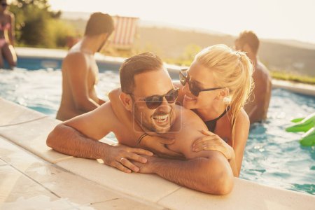 Téléchargez les photos : Couple amoureux lors d'une fête d'été au bord de la piscine, penché au bord d'une piscine, bronzer et s'amuser - en image libre de droit