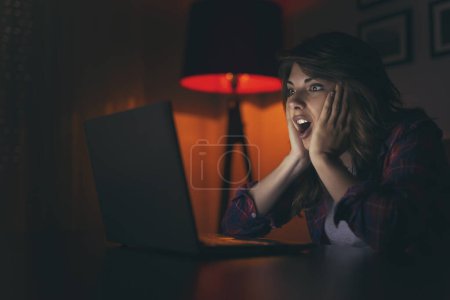 Photo for Beautiful young woman enjoying her leisure time, watching a movie on her laptop computer - Royalty Free Image