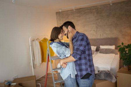 Photo for Beautiful young couple in love moving in together, hugging and kissing in their new home - Royalty Free Image