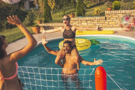 Foto de Grupo de amigos divirtiéndose en una fiesta de verano junto a la piscina, jugando voleibol en la piscina - Imagen libre de derechos