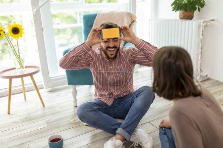 Couple having fun at home playing charades, explaining and guessing the words from a smartphone app