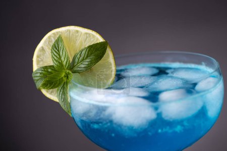 Foto de Detalle de cóctel laguna azul con licor de curazao azul, vodka, zumo de limón y refresco, decorado con rodajas de limón y hojas de menta. Enfoque selectivo en las hojas de menta - Imagen libre de derechos