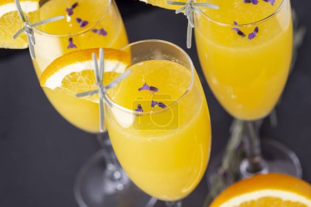 Téléchargez les photos : Vue panoramique des cocktails mimosa au jus d'orange et champagne décorés de feuilles et fleurs de lavande et de tranches d'orange - en image libre de droit