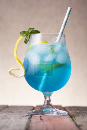 Foto de Cóctel laguna azul con licor de curazao azul, vodka, zumo de limón y refrescos, decorado con rodajas de limón y hojas de menta - Imagen libre de derechos