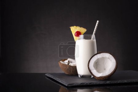Photo for Glass of pina colada cocktail with dark rum, pineapple juice and coconut cream, decorated with pineapple slices and maraschino cherry - Royalty Free Image