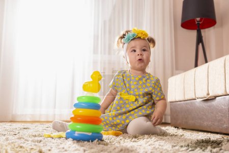 Foto de Hermosa niña jugando con pilas de colores de diferentes círculos de tamaño juguete didáctico y buscando sorprendido - Imagen libre de derechos