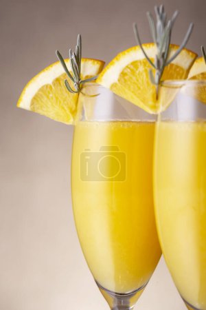Téléchargez les photos : Détail des cocktails mimosa dans des verres à champagne au jus d'orange et au vin mousseux décorés de feuilles de lavande et de tranches d'orange - en image libre de droit