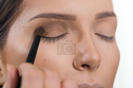 Photo for Make up artist working in a make up studio, shading the female client's eyelids - Royalty Free Image