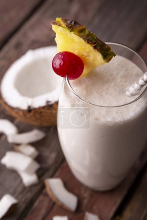 Téléchargez les photos : Vue en angle élevé d'un verre de cocktail pina colada au rhum foncé, au jus d'ananas et à la crème de coco, décoré de tranches d'ananas et de cerise marasquin - en image libre de droit
