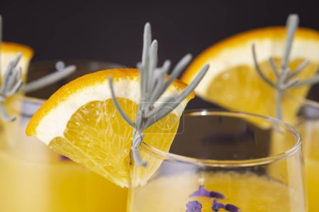 Téléchargez les photos : Détail des cocktails mimosa dans des verres à champagne avec du jus d'orange et du vin mousseux décoré avec des feuilles de lavande et des tranches d'orange. Focus sélectif sur la tranche d'orange sur le verre - en image libre de droit