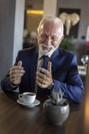 Téléchargez les photos : Homme d'affaires senior lors d'une réunion dans un restaurant, avoir une conversation avec un partenaire d'affaires et boire du café - en image libre de droit
