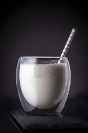 Foto de Cóctel de piña colada con ron oscuro, jugo de piña y crema de coco servido con paja para beber en una bandeja de piedra negra - Imagen libre de derechos