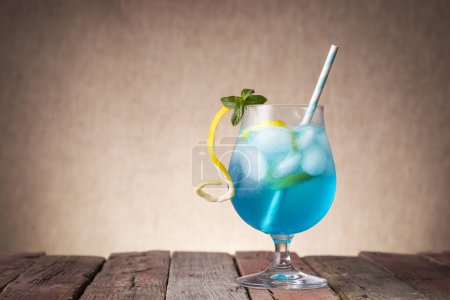 Téléchargez les photos : Cocktail lagon bleu avec liqueur de curaçao bleu, vodka, jus de citron et soda, décoré de tranches de citron et de feuilles de menthe - en image libre de droit