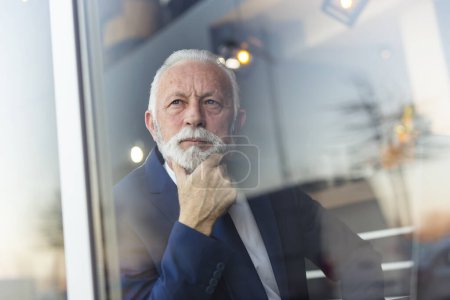 Foto de Retrato de un hombre de negocios mayor sentado en una mesa de restaurante, mirando pensativamente - Imagen libre de derechos