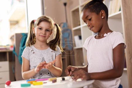 Photo for Two preschoolers playing with colorful plasticine and having fun. Focus on the girl on the left - Royalty Free Image