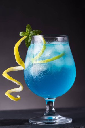 Foto de Cóctel laguna azul con licor de curazao azul, vodka, zumo de limón y refrescos, decorado con rodajas de limón y hojas de menta. Enfoque selectivo en el vidrio - Imagen libre de derechos