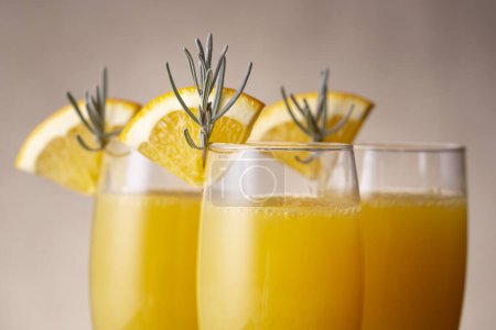 Foto de Detalle de cócteles mimosa en copas de champán con zumo de naranja y vino espumoso decorado con hojas de lavanda y rodajas de naranja - Imagen libre de derechos