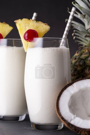 Téléchargez les photos : Deux verres de cocktail pina colada au rhum foncé, jus d'ananas et crème de coco, décorés de tranches d'ananas et de cerise marasquin - en image libre de droit