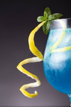 Téléchargez les photos : Détail du cocktail lagon bleu avec liqueur de curaçao bleu, vodka, jus de citron et soda, décoré de tranches de citron et de feuilles de menthe. Focus sélectif sur les feuilles de menthe - en image libre de droit