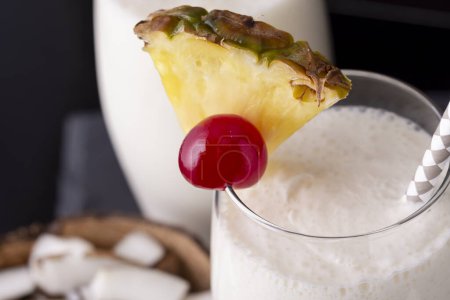 Photo for High angle view of two glasses of pina colada cocktail with dark rum, pineapple juice and coconut cream, decorated with pineapple slices and maraschino cherry - Royalty Free Image