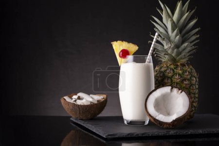 Téléchargez les photos : Verre de cocktail pina colada au rhum foncé, jus d'ananas et crème de coco, décoré de tranches d'ananas et de cerise marasquin - en image libre de droit